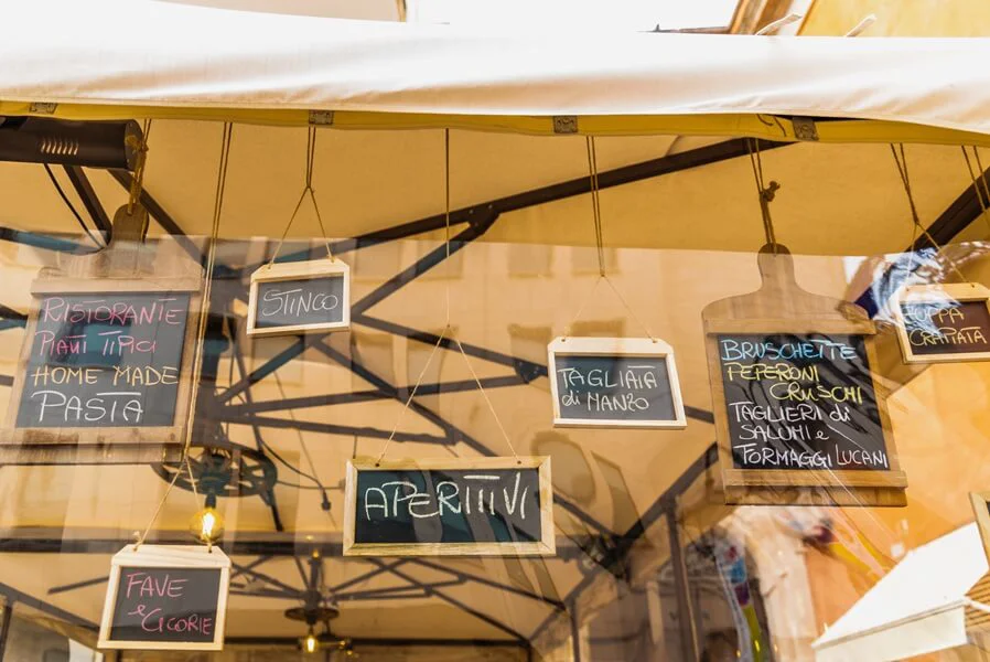 An Italian restaurant menu displayed outside under a canopy.